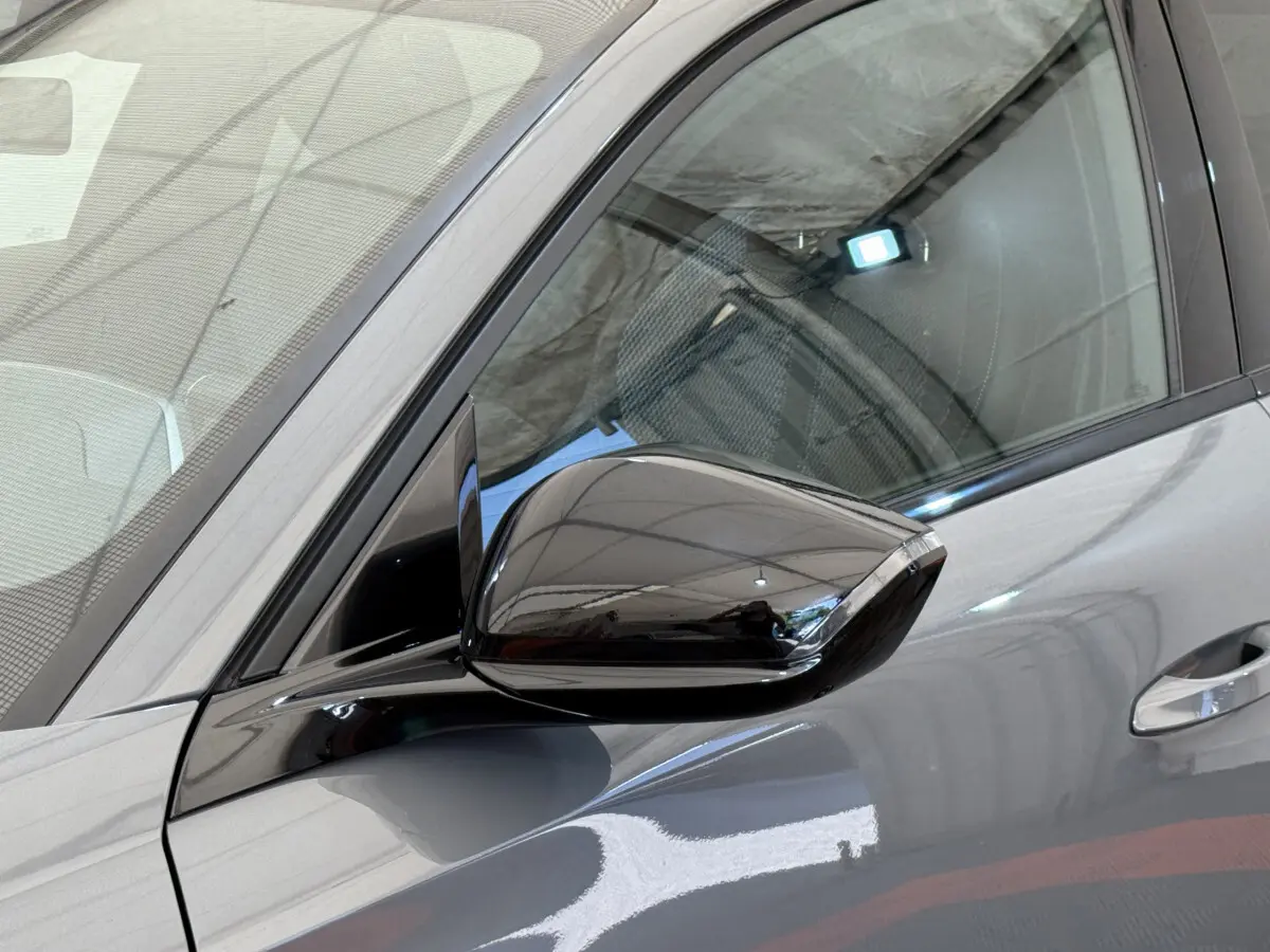Gros plan sur le rétroviseur côté gauche d'une Peugeot 308 Hybrid 136 e-DCS6 GT gris foncé avec carrosserie brillante.