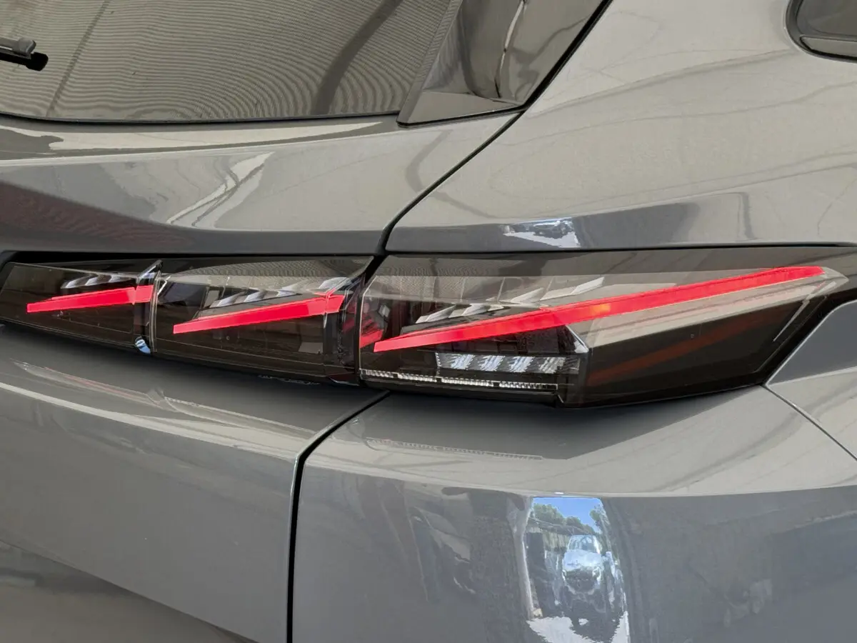 Gros plan sur le feu arrière droit rouge vif d'une Peugeot 308 Hybrid 136 e-DCS6 GT gris foncé 2024.