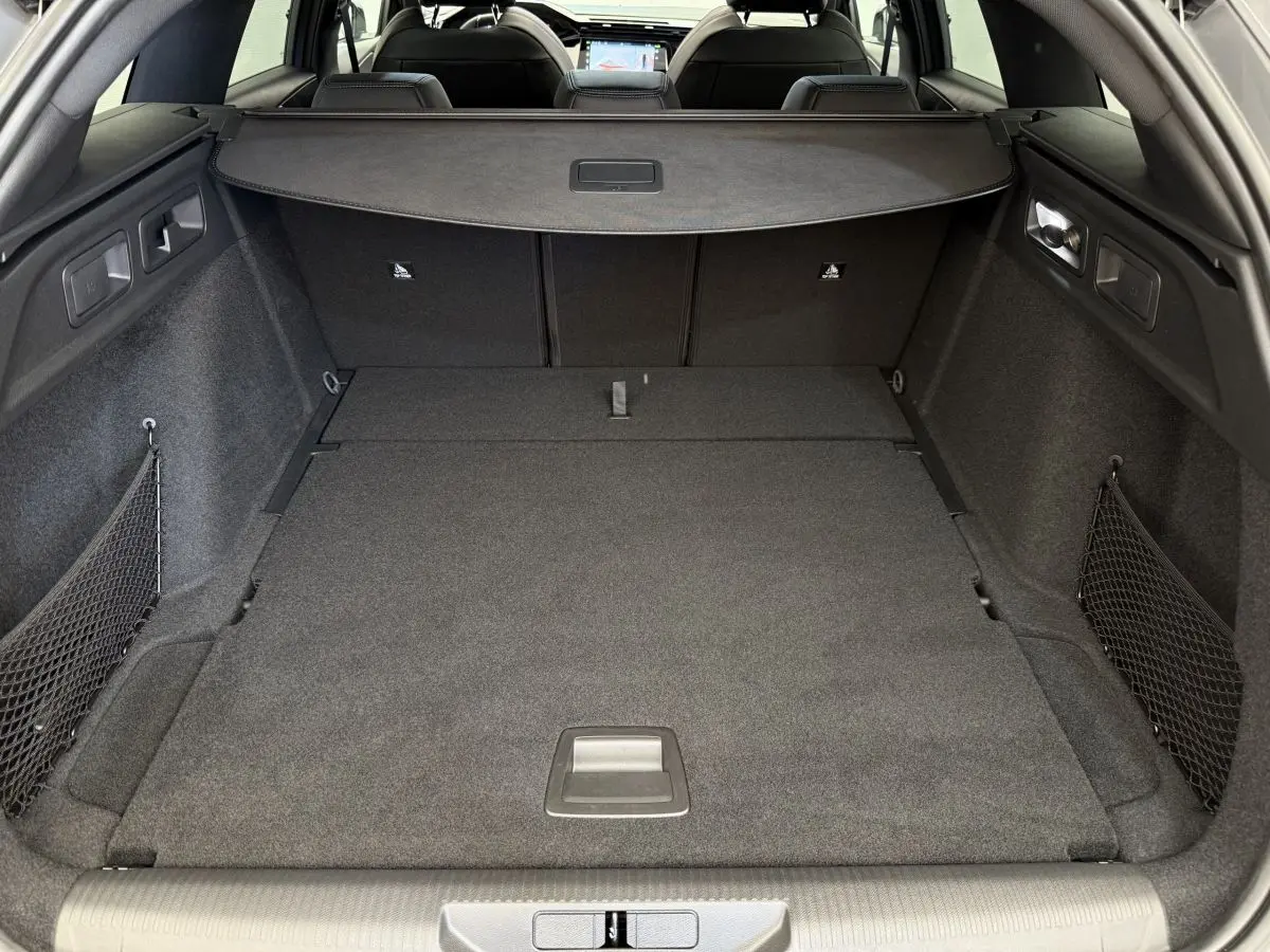 Coffre spacieux de la Peugeot 308 Hybrid gris foncé vu de l'arrière avec banquette rabattue et filet de rangement.