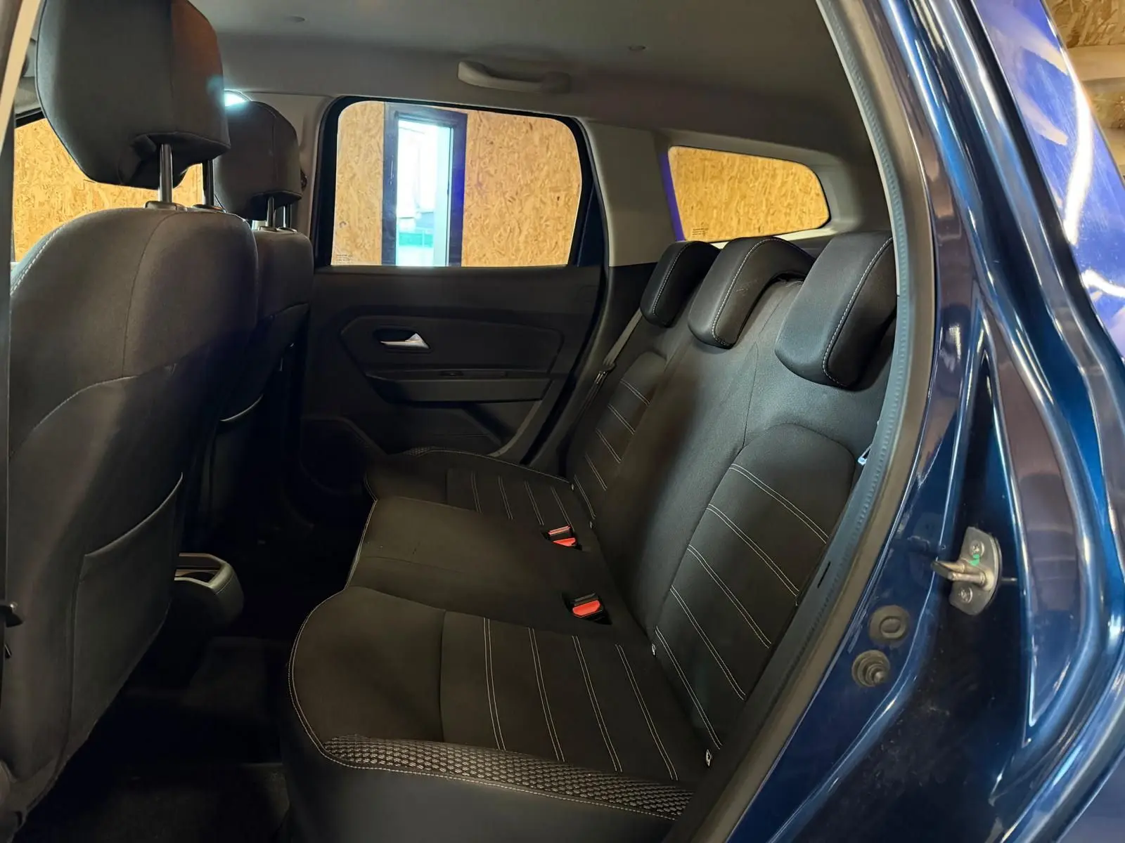 Vue latérale droite de l'intérieur arrière du Dacia Duster bleu, montrant la banquette tissu Prestige avec appuie-têtes.