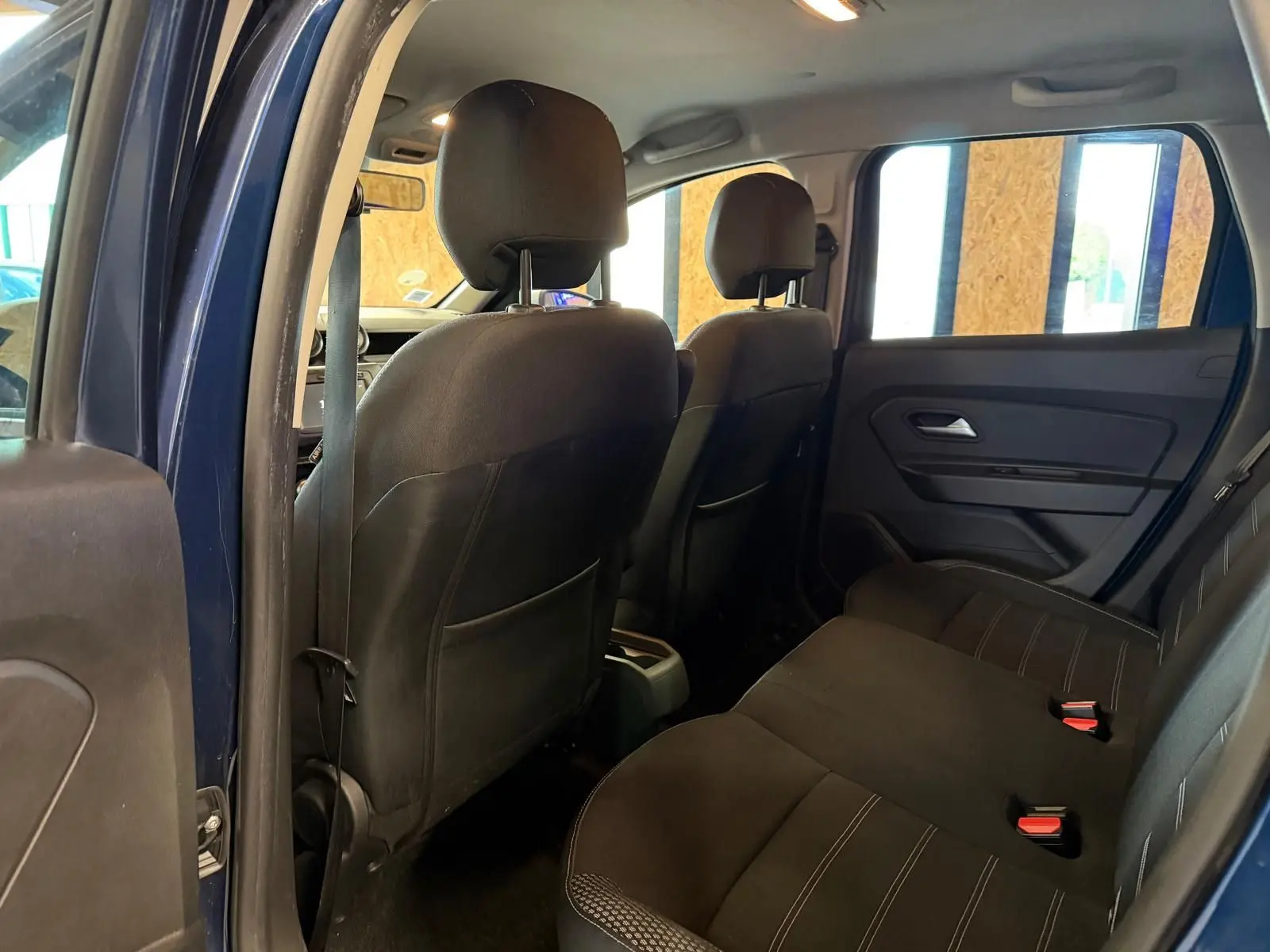 Vue intérieure arrière du Dacia Duster bleu, montrant les sièges tissu Prestige noirs et les appuie-têtes arrière.