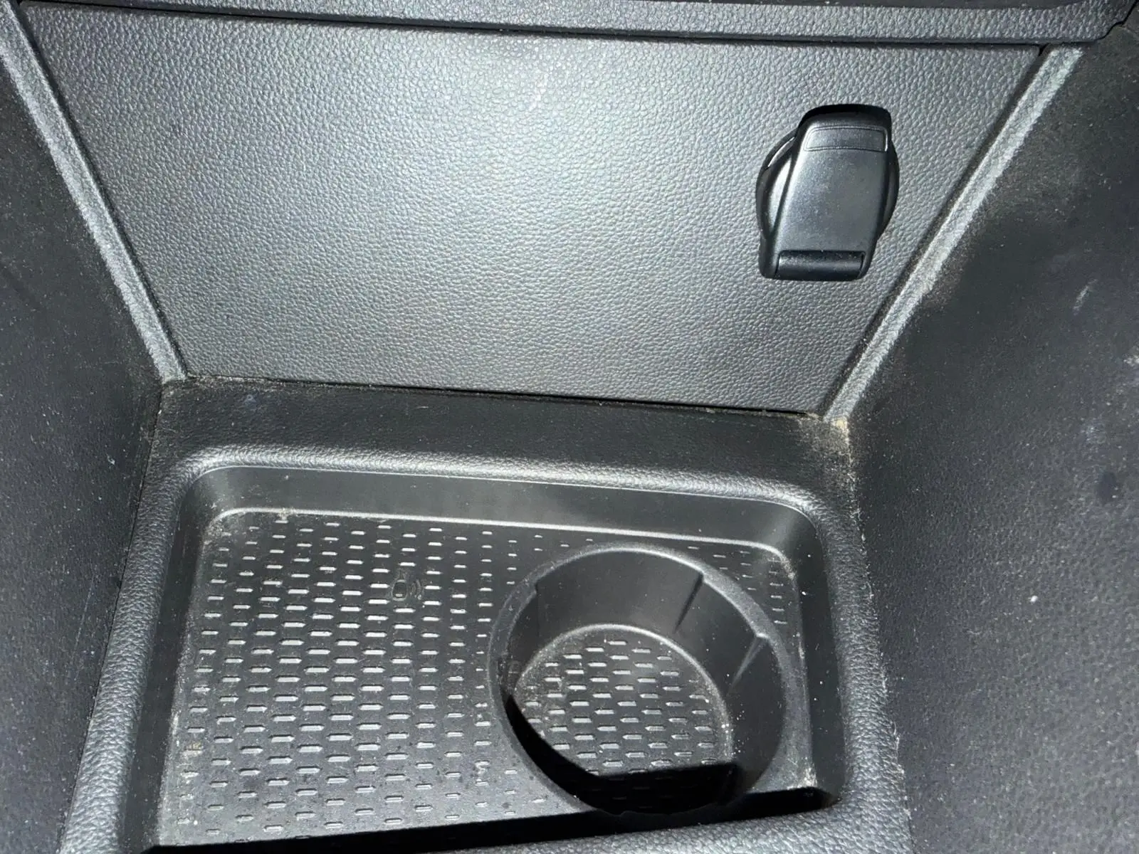 Prise 12V et rangement intérieur en plastique noir du coffre du Dacia Duster bleu, vue rapprochée du plancher.