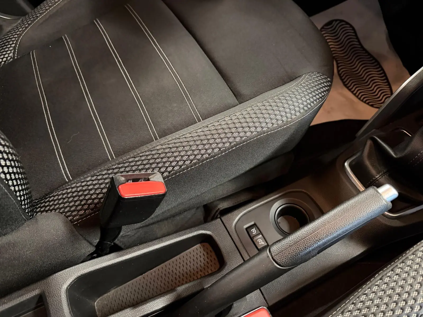 Gros plan sur la console centrale et siège tissu noir à surpiqûres du Dacia Duster bleu diesel, frein à main levé.