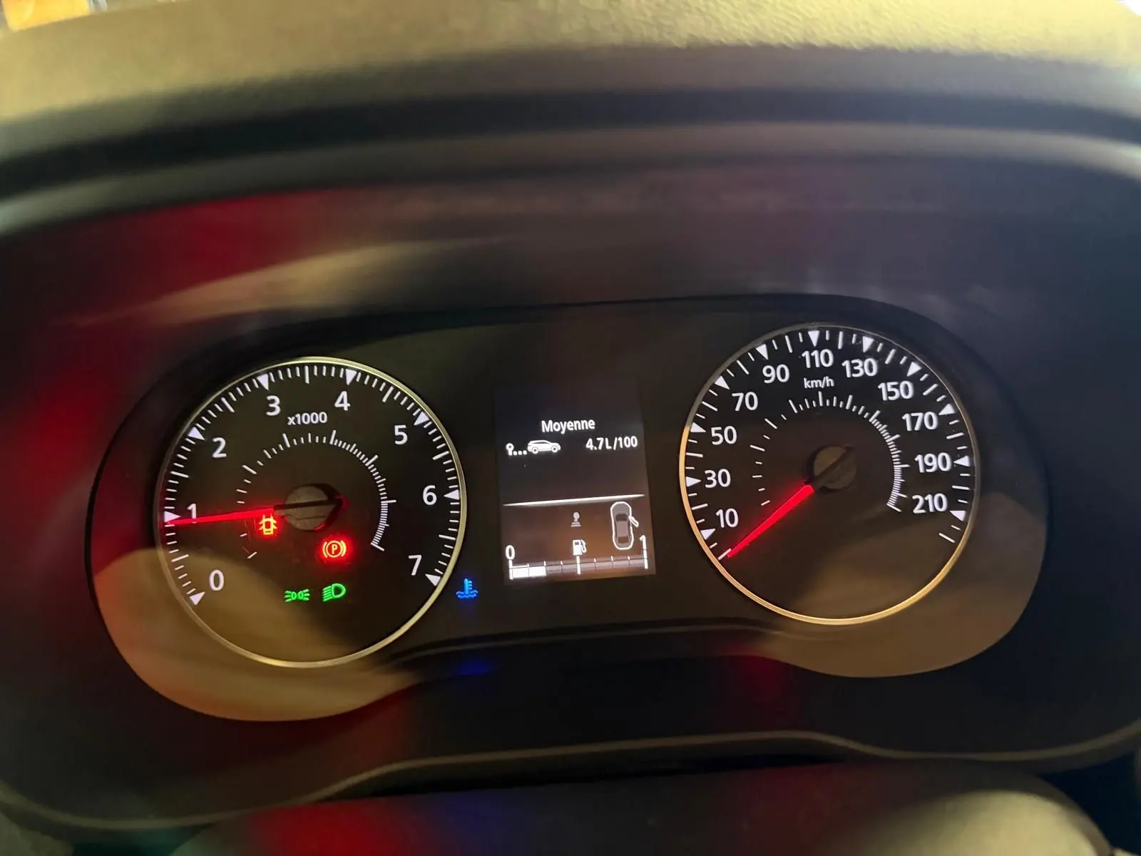 Tableau de bord du Dacia Duster bleu, affichant compte-tours, vitesse et consommation moyenne à 4,7 l/100 km.