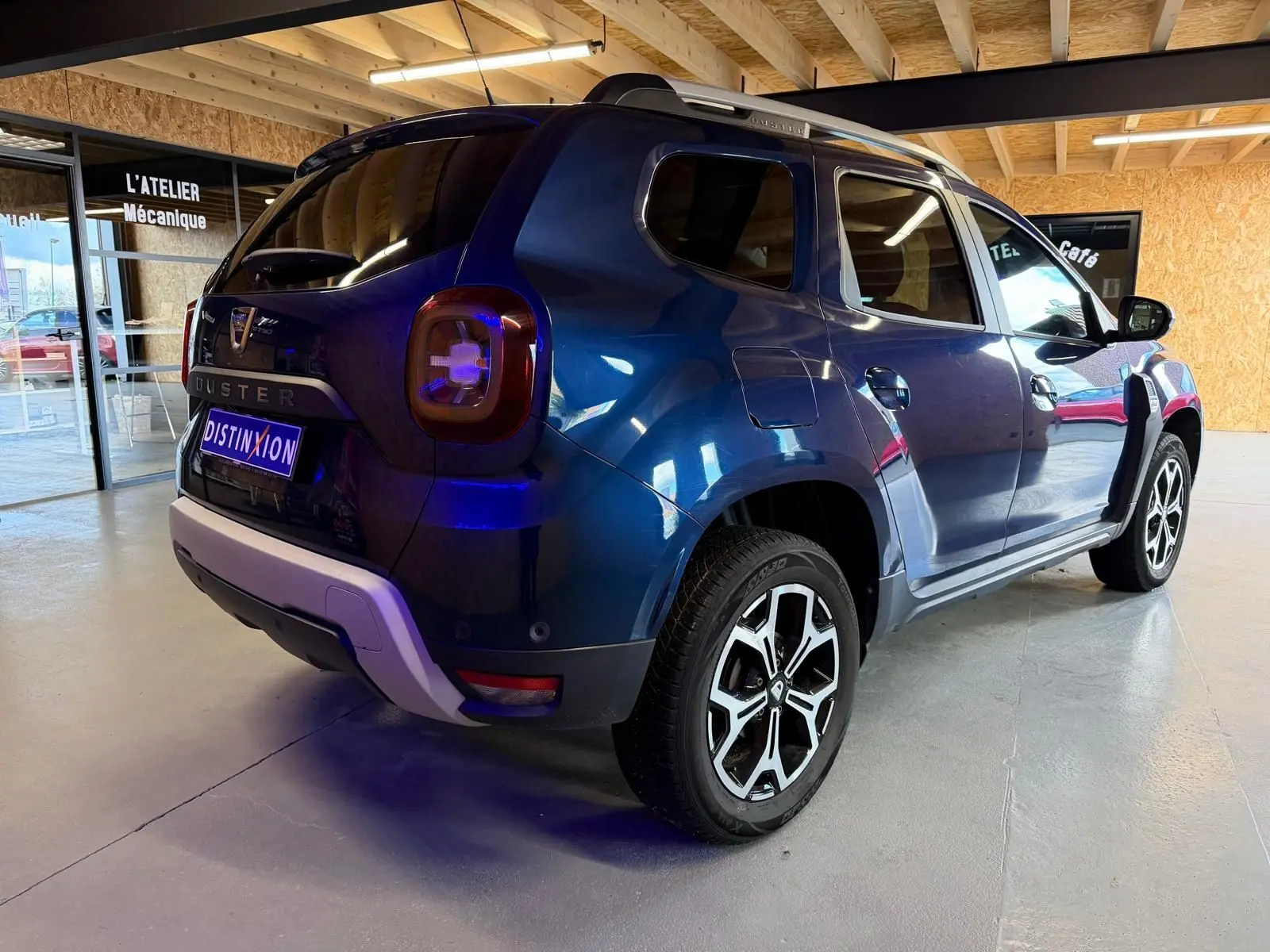 Vue 3/4 arrière droite d'un Dacia Duster bleu avec jantes alliage 17'' Maldives et bouclier arrière ton carrosserie.