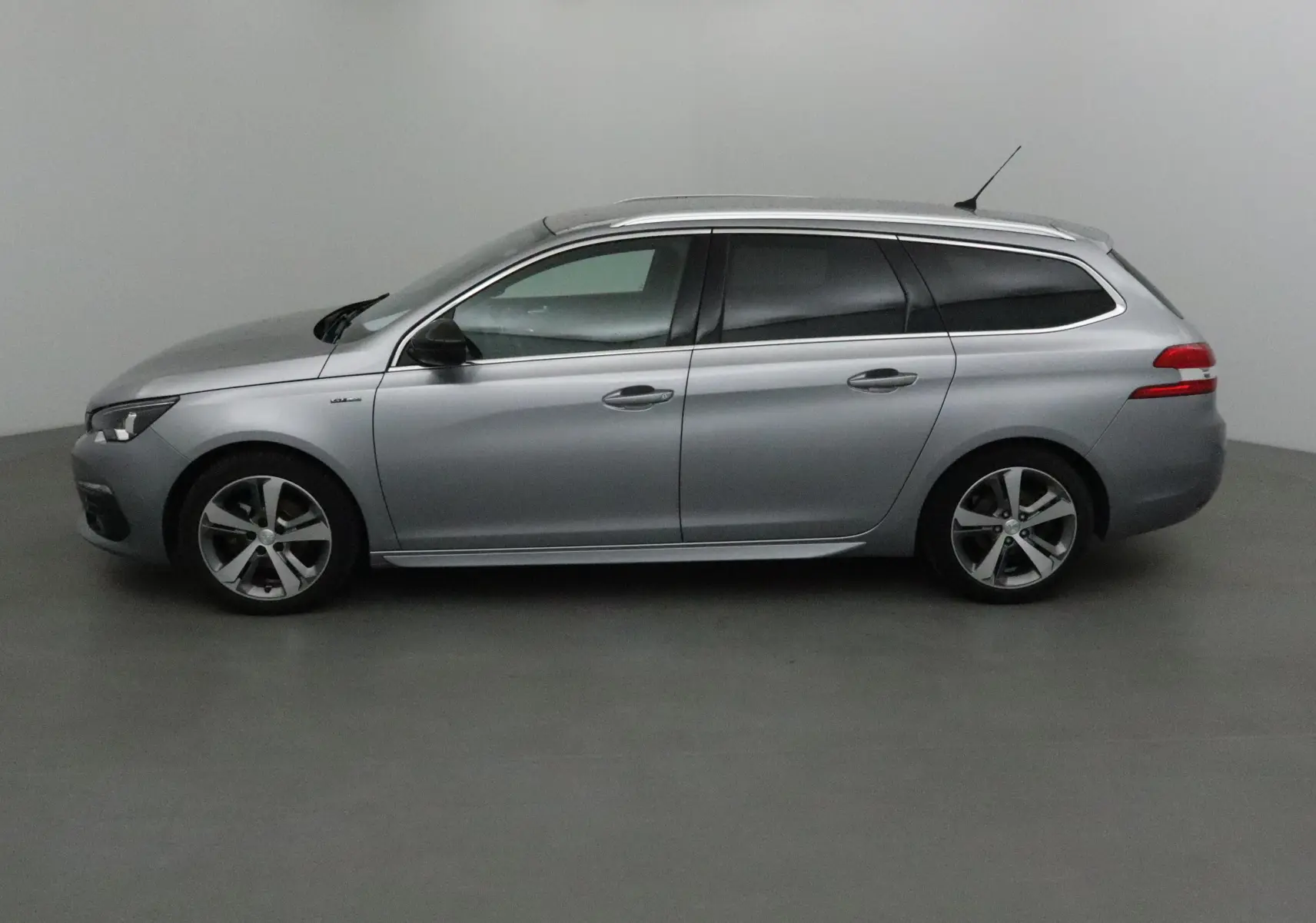 Profil droit d'une Peugeot 308 SW 1.5 BlueHDi 130 GT Line gris Artense avec jantes alliage et vitres teintées.