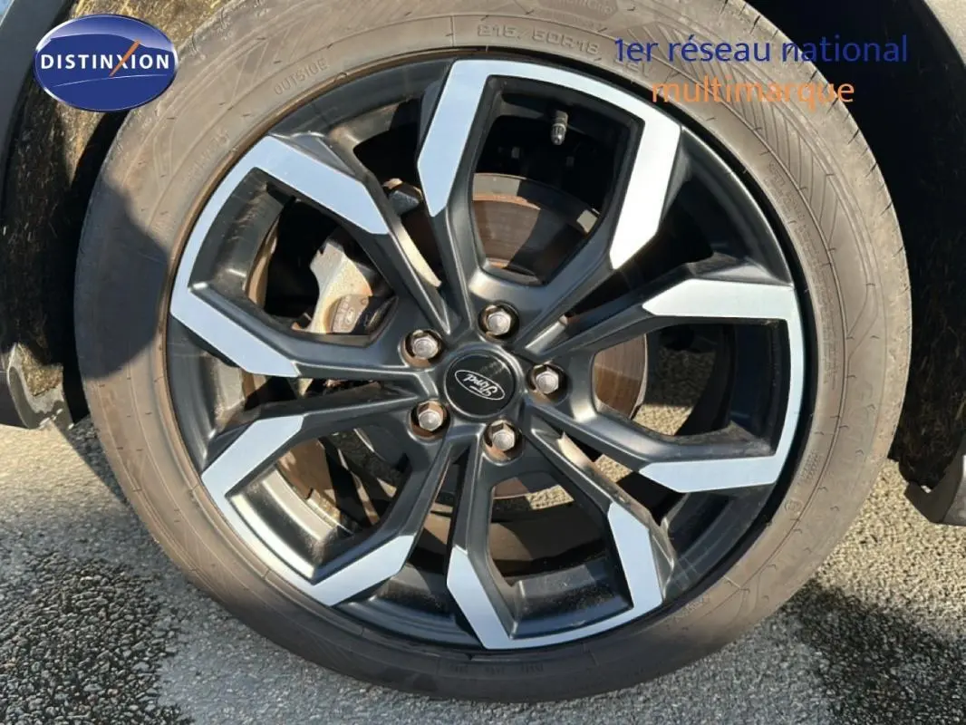 Gros plan sur la jante alliage 18 pouces noire et argentée du Ford Puma gris foncé, roue avant droite visible.