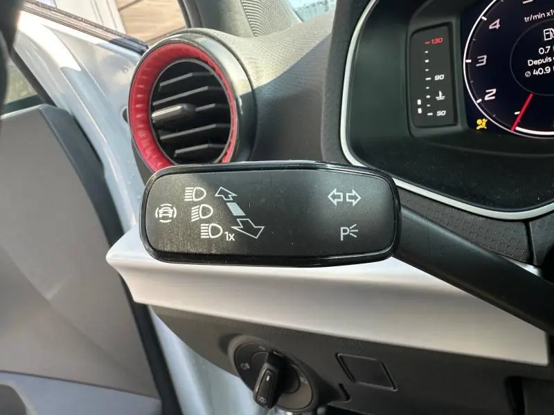 Gros plan sur la commande de clignotants et feux du SEAT Arona 2025, avec aérateur rond noir et rouge en arrière-plan.