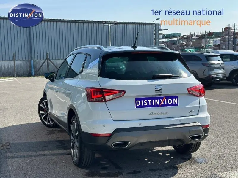 Vue 3/4 arrière droite d'un SEAT Arona 2025 blanc Candy avec toit noir, feux LED et double sortie d'échappement.