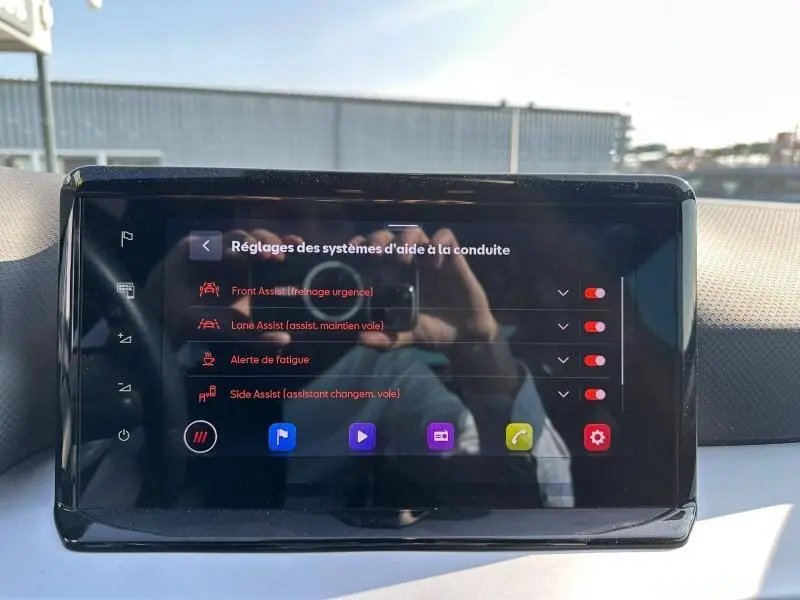 Écran tactile central du SEAT Arona 2025 affichant les réglages des aides à la conduite avec reflet partiel.