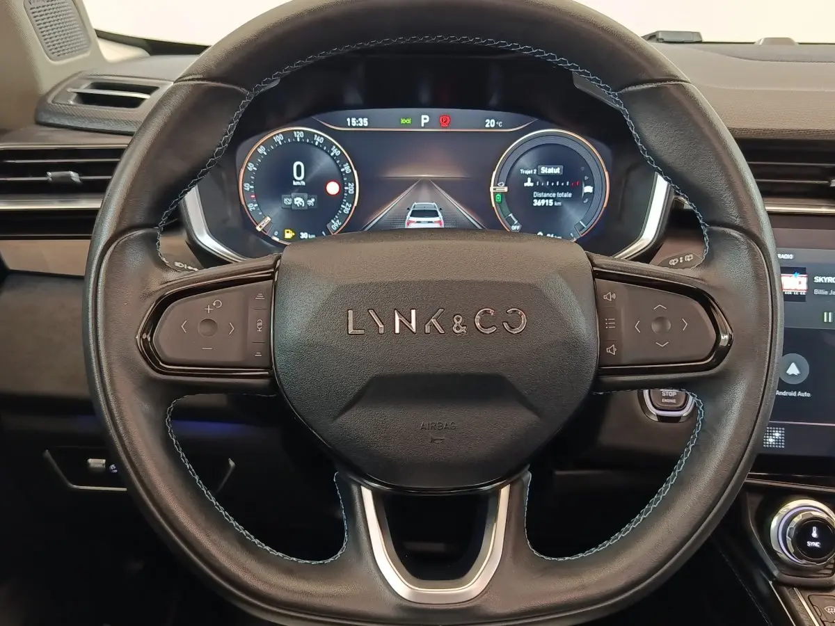 Vue rapprochée du volant noir avec logo Lynk & Co et tableau de bord numérique affichant les instruments.