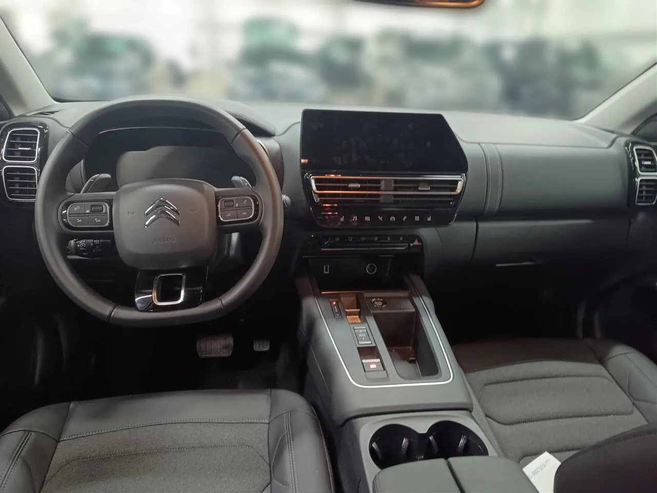 Intérieur noir du Citroën C5 Aircross Hybrid 2025, vue frontale sur le volant, tableau de bord et console centrale moderne.