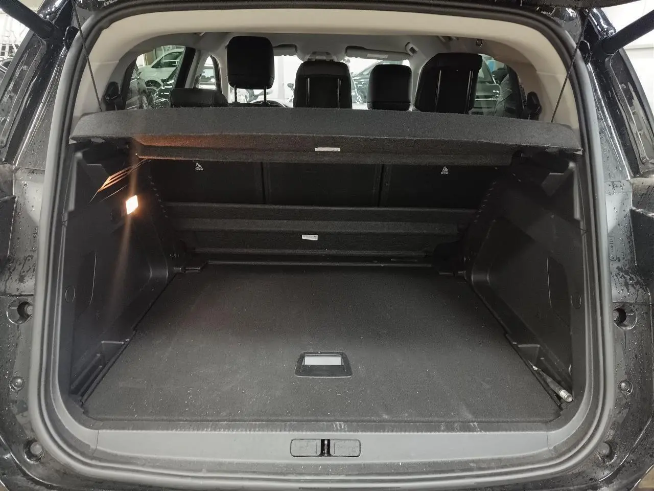 Coffre ouvert vu de l'arrière d'un Citroën C5 Aircross Hybrid noir Perla avec banquette arrière et hayon électrique.