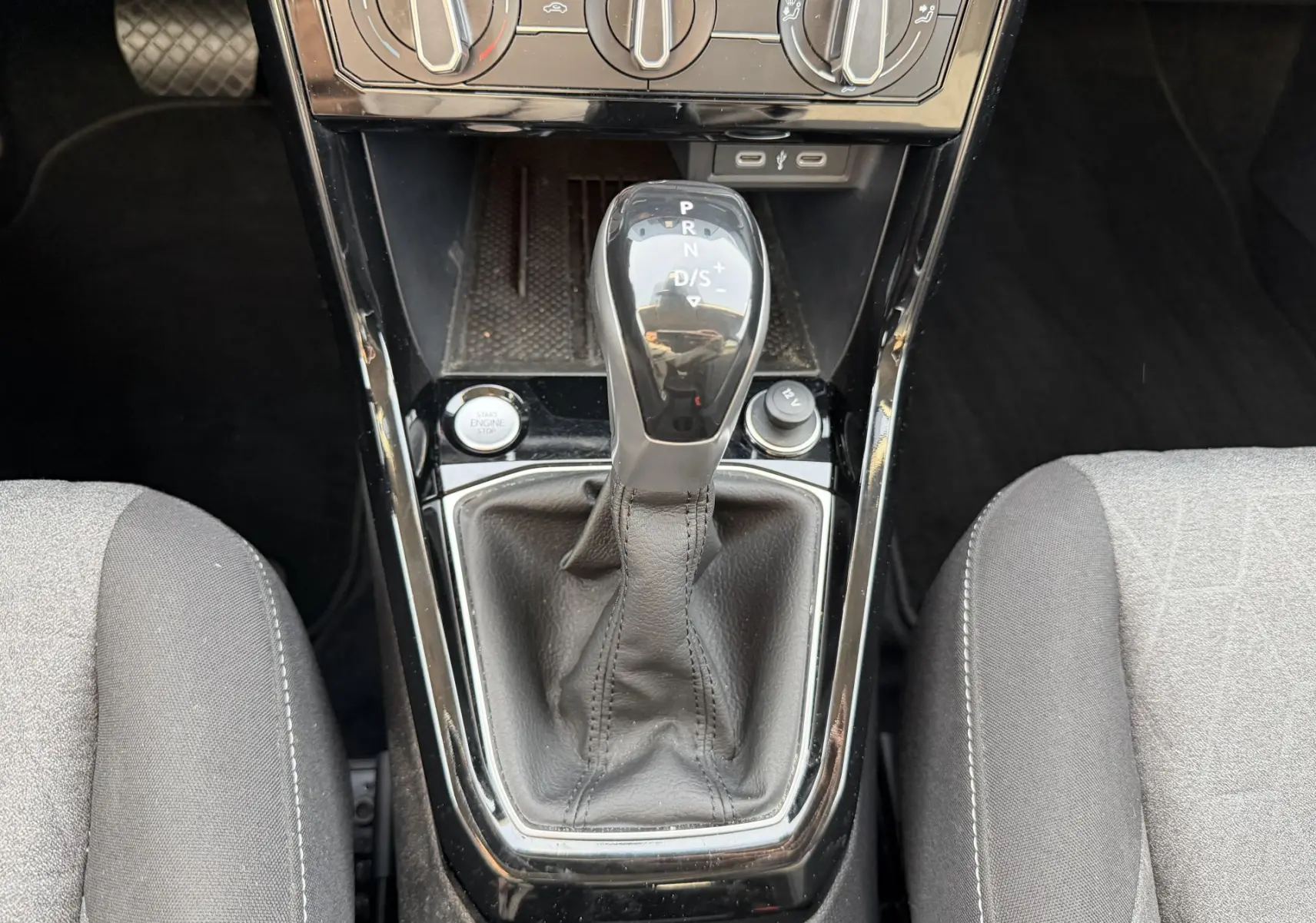 Gros plan sur la console centrale du Volkswagen T-Cross gris 2025, avec levier de vitesse DSG7 et commandes de climatisation.