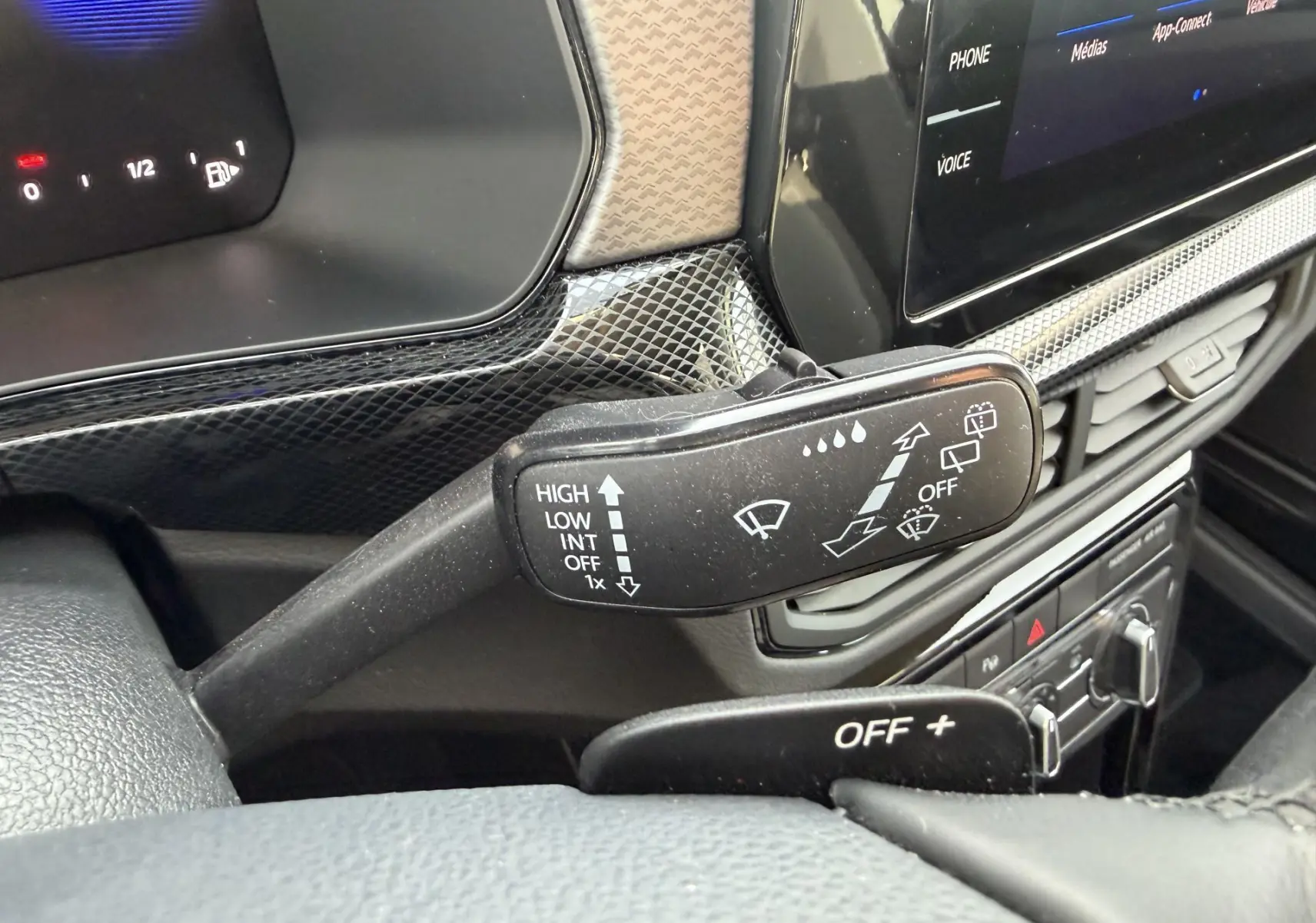 Gros plan sur la commande d’essuie-glace du Volkswagen T-Cross 2025, intérieur noir avec écran tactile visible.