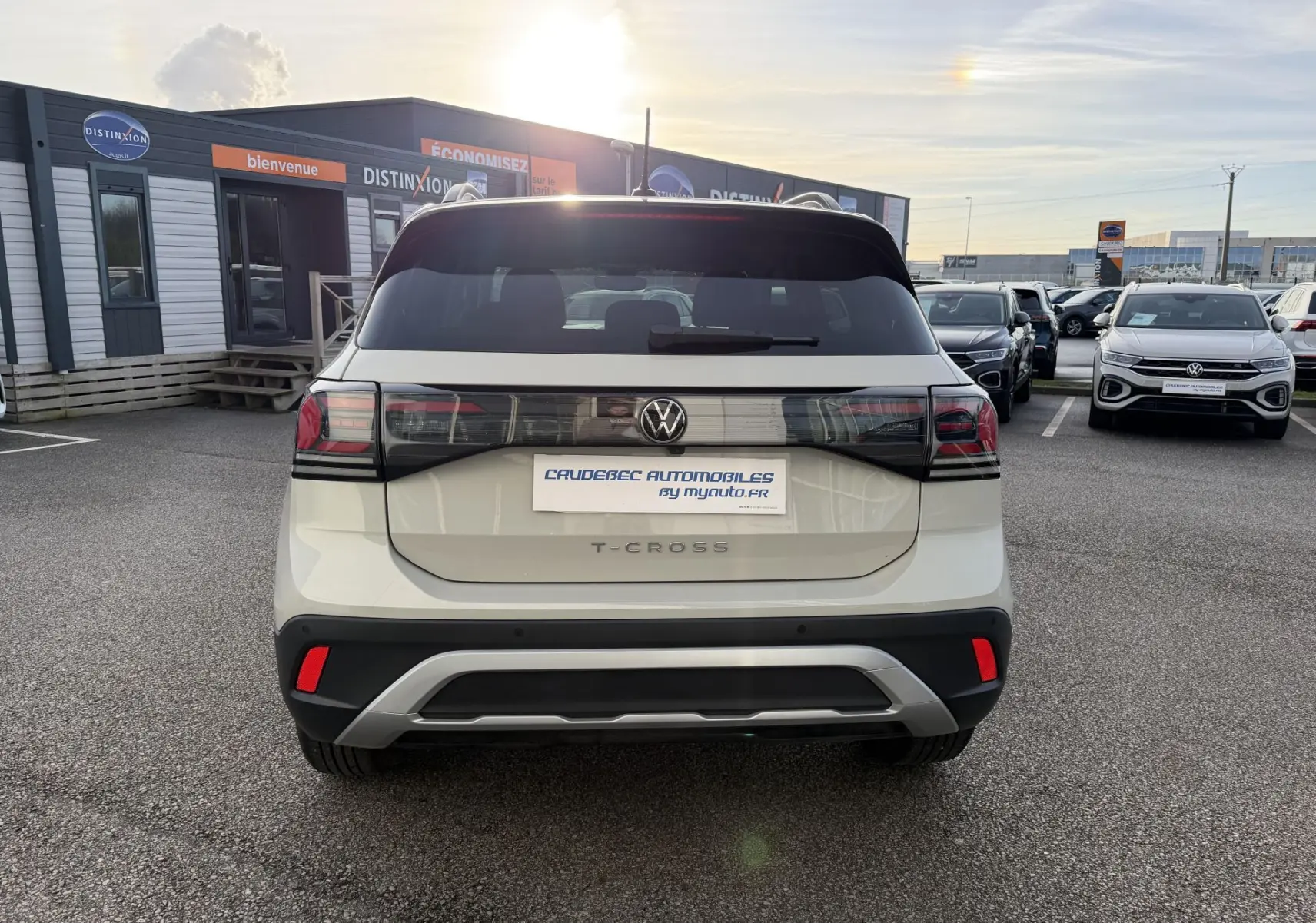 Vue arrière d'un Volkswagen T-Cross gris clair avec feux arrière LED et logo VW central sur un parking.