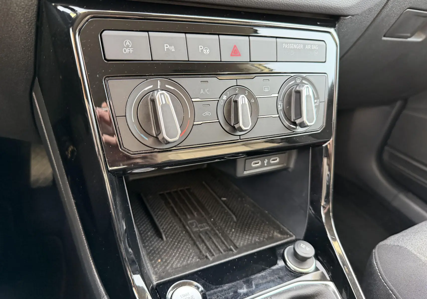 Vue rapprochée de la console centrale du Volkswagen T-Cross 2025, avec commandes de climatisation manuelle et bouton start/stop.