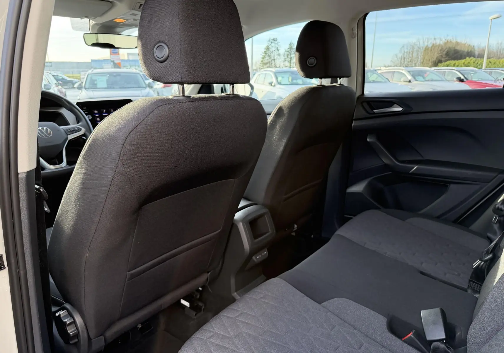 Vue intérieure arrière du Volkswagen T-Cross gris, montrant les sièges arrière et dossiers avant en tissu noir.