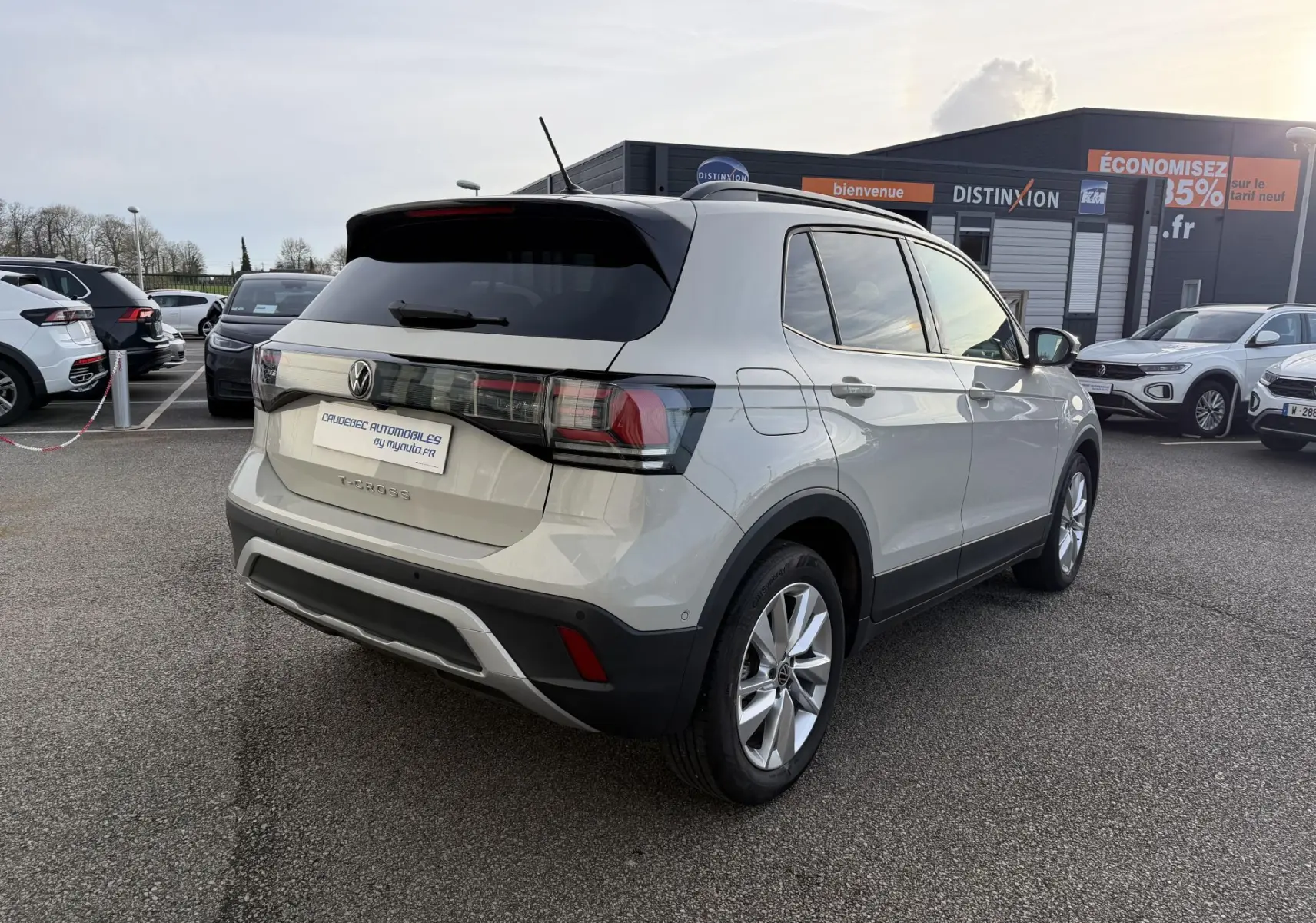 Vue 3/4 arrière droite d'un Volkswagen T-Cross gris avec jantes alliage, garé en extérieur sur un parking.