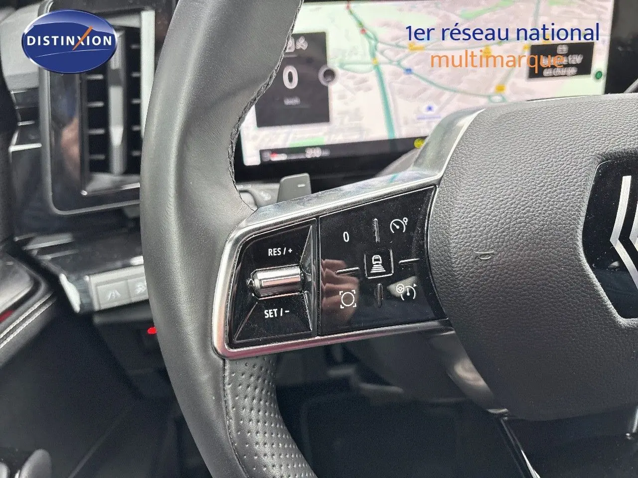 Gros plan sur le volant noir du Renault Austral 2023 avec commandes intégrées et écran de navigation en arrière-plan.