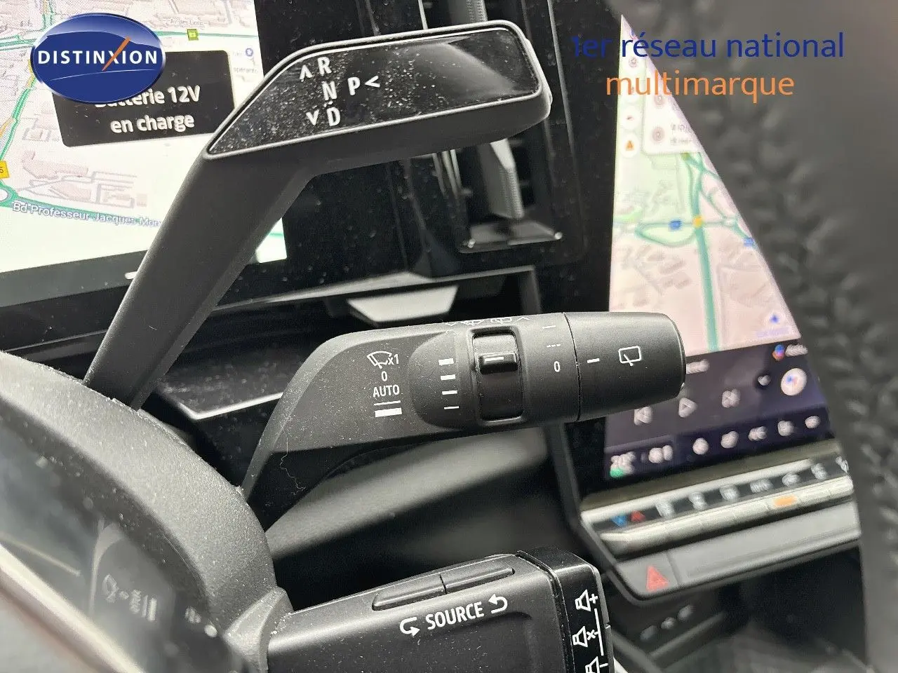 Gros plan sur les commandes au volant du Renault Austral 2023, avec écran tactile et navigation visible en arrière-plan.