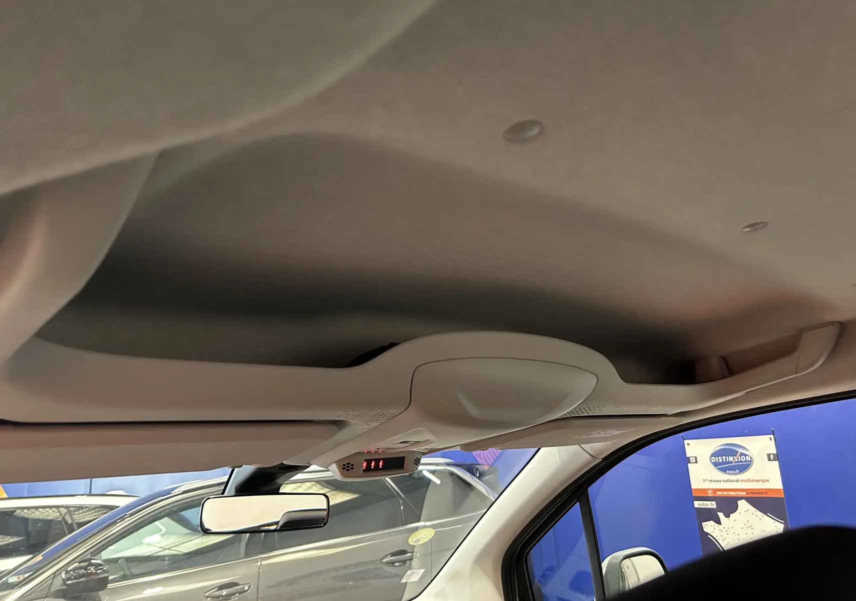 Vue intérieure du plafond avant du Peugeot Rifter gris sable 2019 avec rétroviseur et pare-brise visible côté droit.