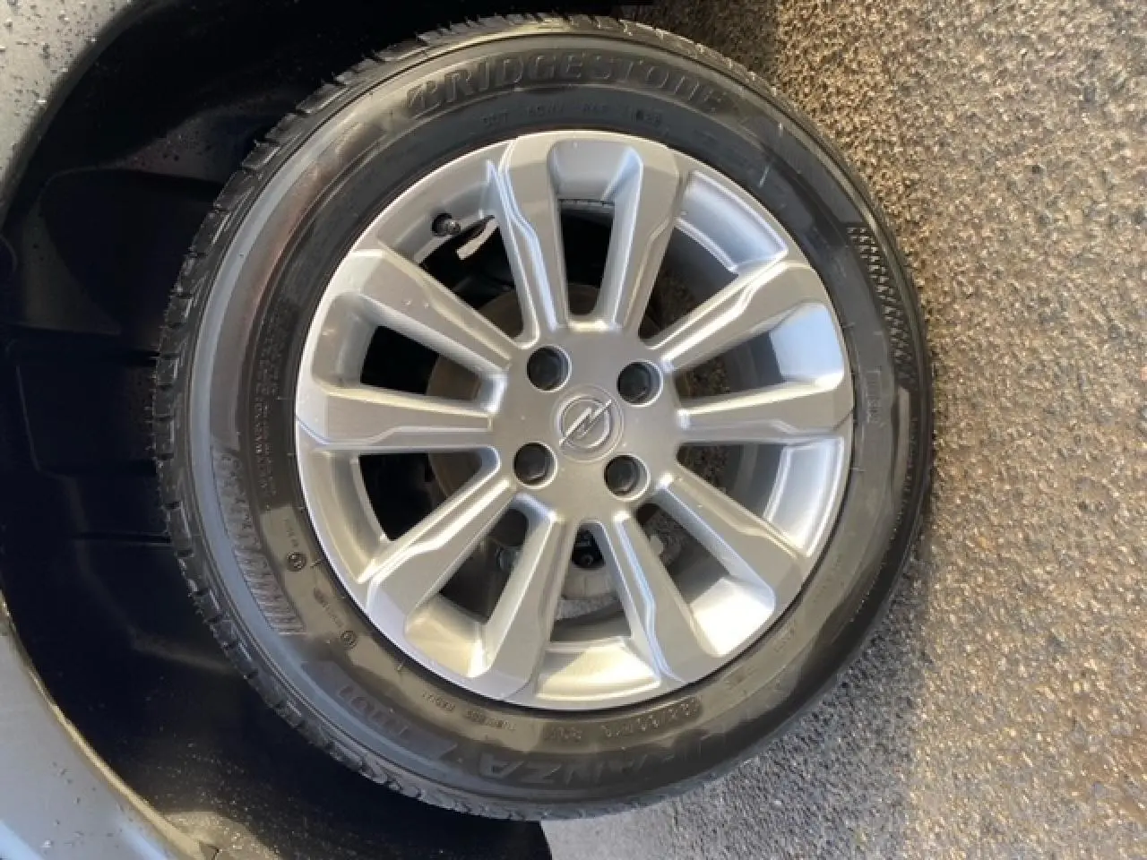 Gros plan sur la roue de secours avec jante alliage argentée et logo Opel au centre, sur fond noir métallisé.