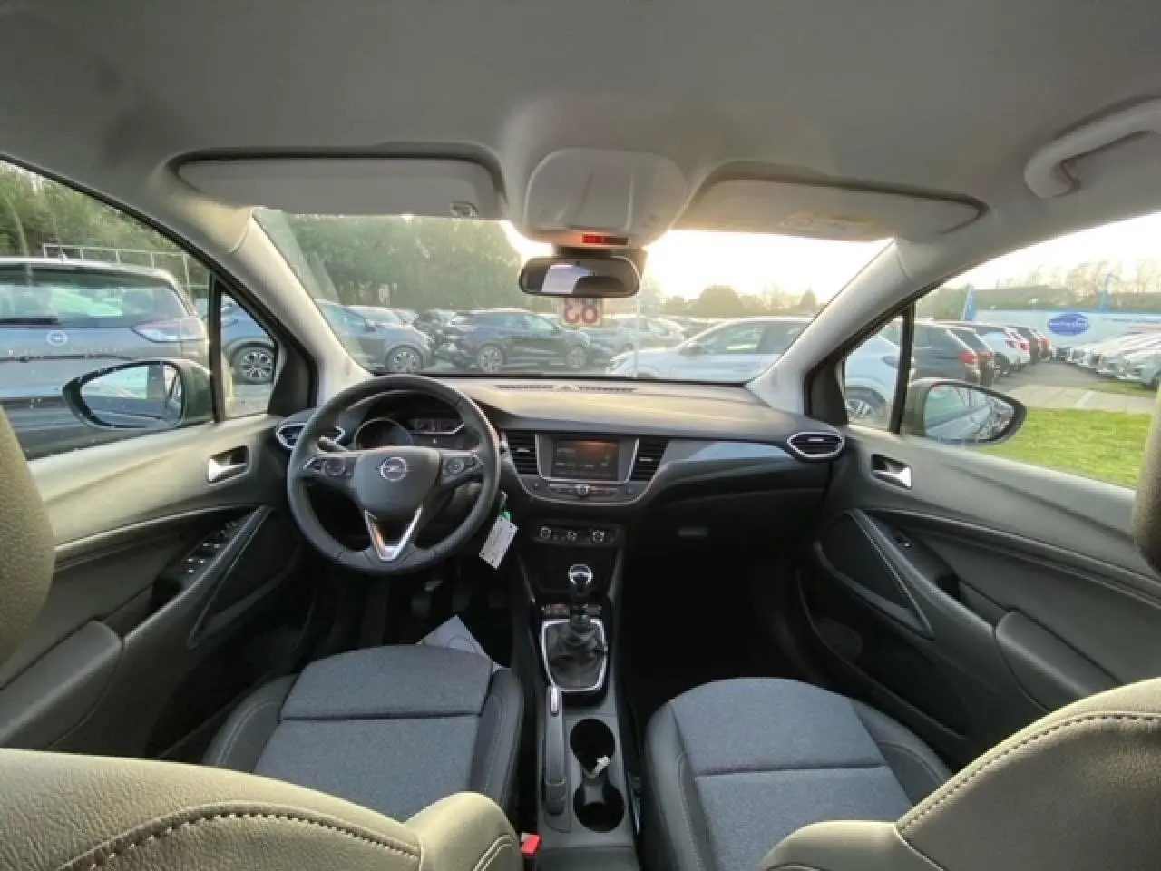 Vue intérieure avant de l'Opel Crossland noir métal 2022, avec tableau de bord moderne et boîte manuelle visible.