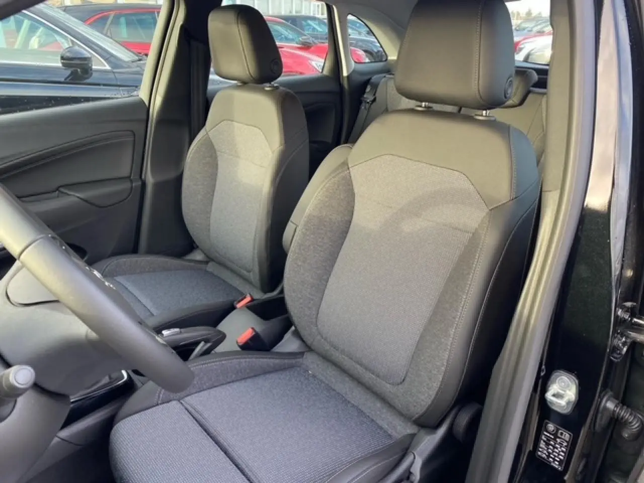Vue intérieure côté conducteur de l'Opel Crossland noir métal 2022, sièges tissu gris avec appuie-têtes réglables.