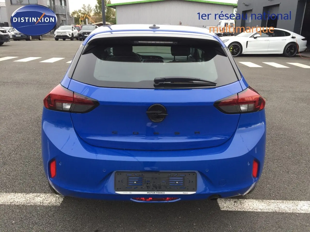 Vue arrière d'une Opel Corsa 2025 bleu voltaik métal avec feux arrière LED et hayon fermé sur parking extérieur.