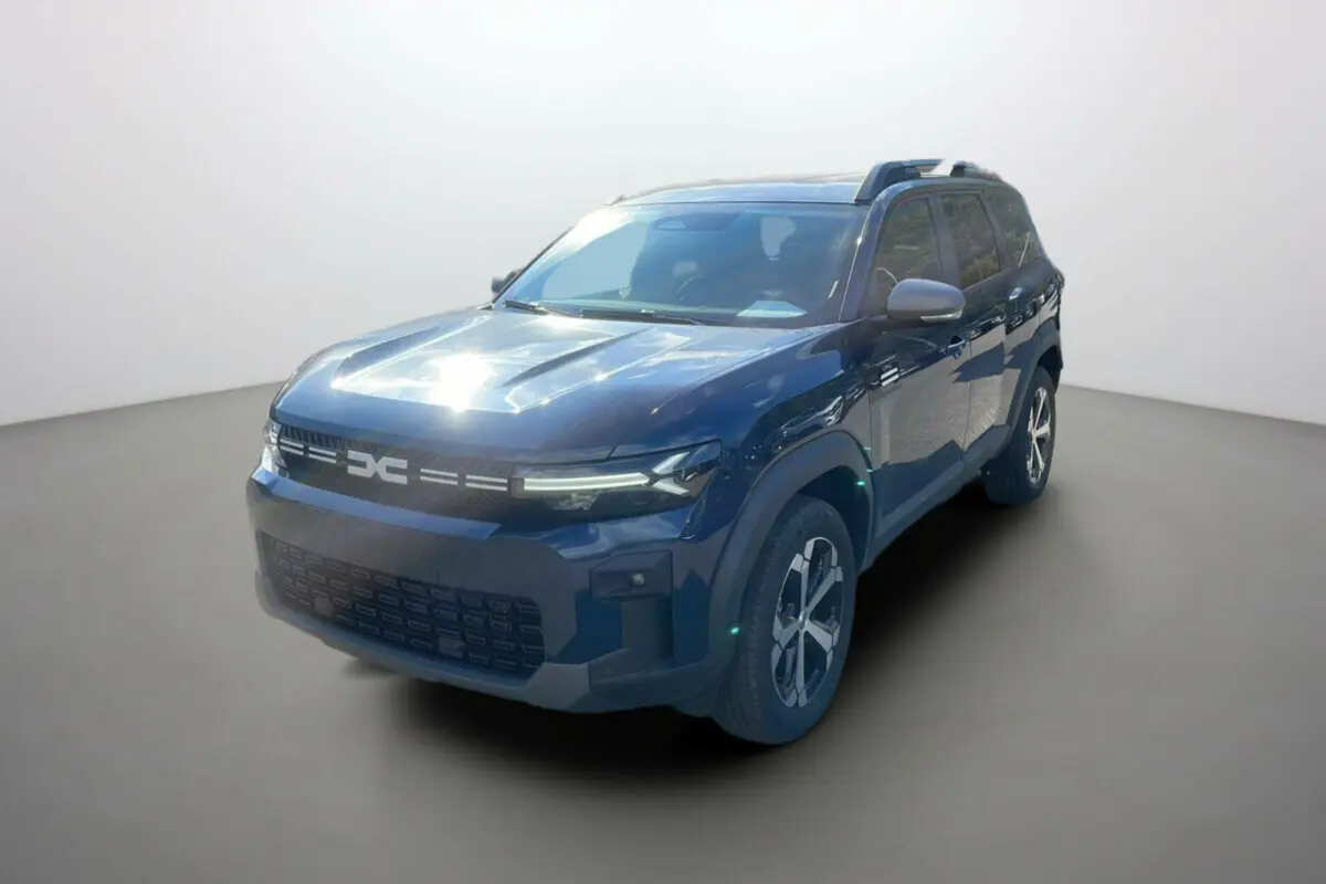 SUV Dacia Bigster bleu indigo en 3/4 avant droit avec barres de toit et jantes alu 18 pouces visibles