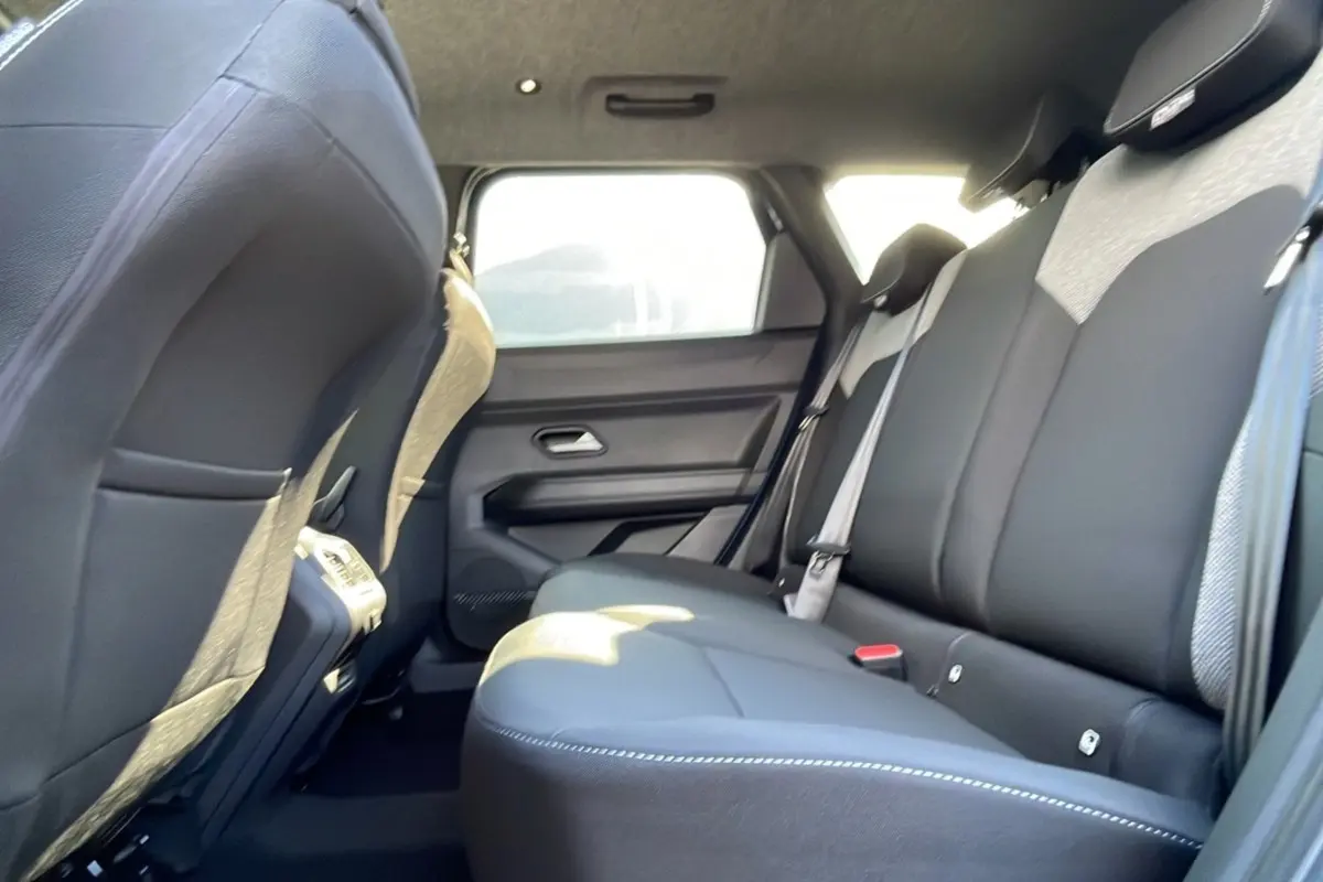 Vue latérale intérieure sur la banquette arrière en tissu gris et noir du Dacia Bigster Hybrid 155 Journey City 2025.