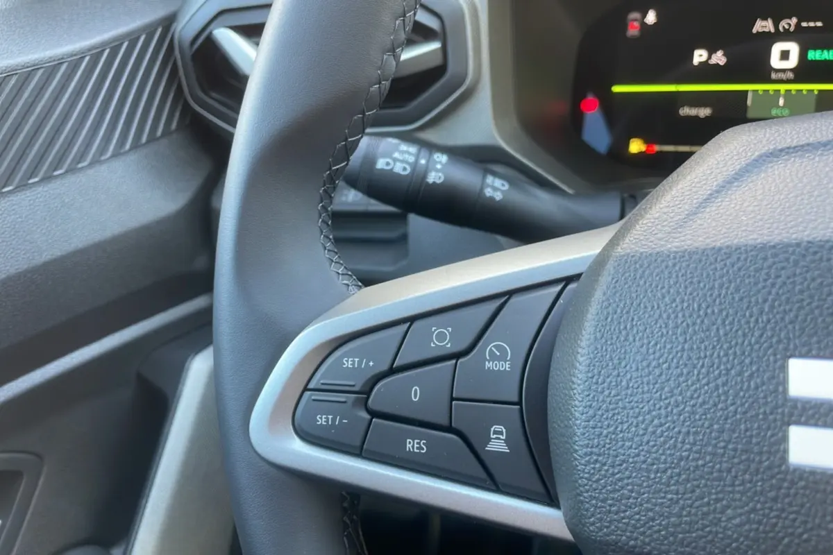 Gros plan sur les commandes au volant cuir du DACIA Bigster Hybrid 155 Journey City, tableau de bord digital en arrière-plan.