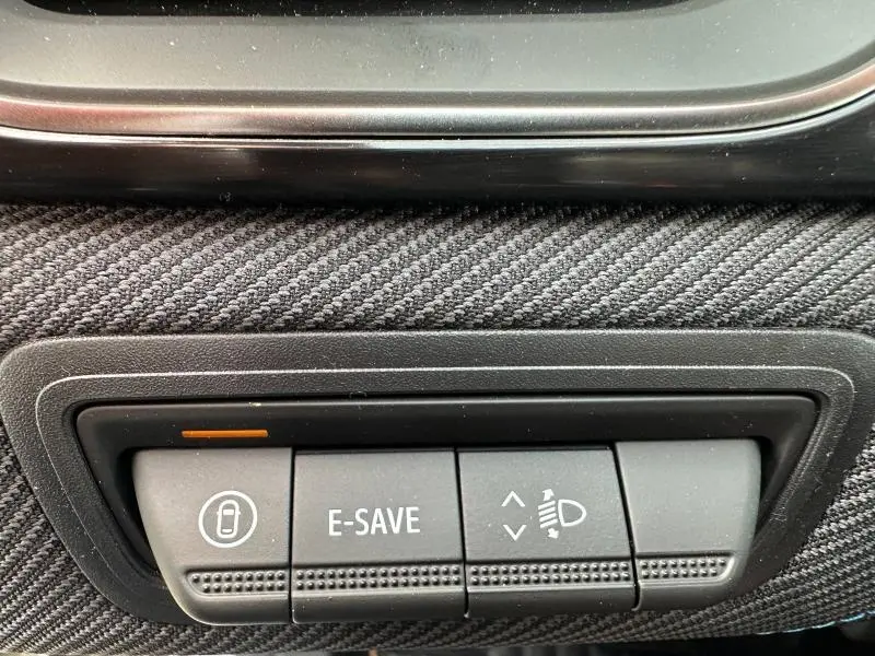 Boutons de commande intérieurs du Renault Captur 2026, avec fonction E-SAVE et réglage des phares, sur tissu gris texturé.