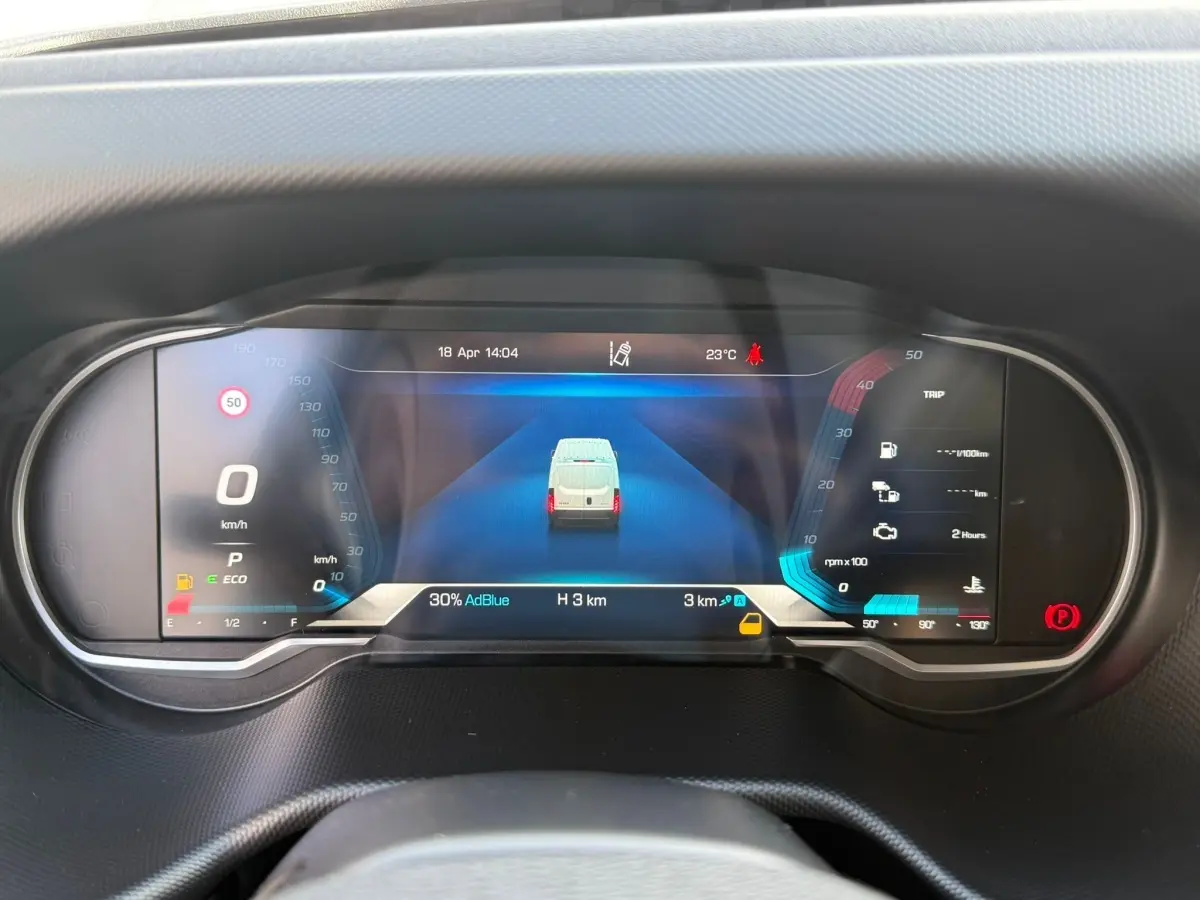 Vue rapprochée du tableau de bord numérique du Iveco Daily blanc, affichant la vitesse à 0 km/h et l'autonomie AdBlue.