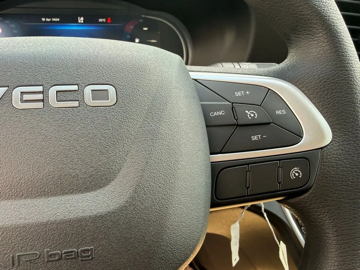 Gros plan sur le volant noir de l'Iveco Daily 35S18 2026, montrant les commandes de régulateur de vitesse à droite.