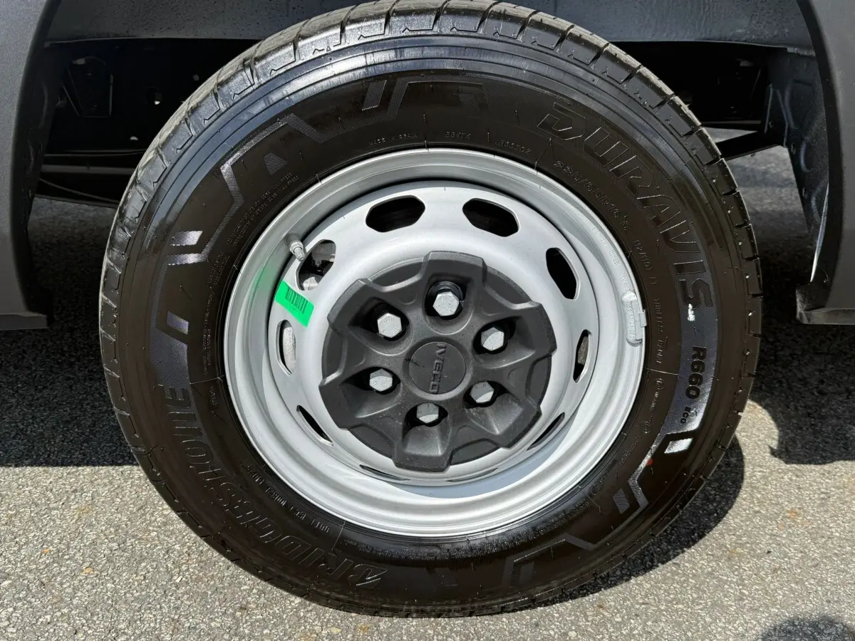 Gros plan sur la roue avant droite du fourgon Iveco Daily blanc, mettant en valeur la jante acier et le pneu Bridgestone.