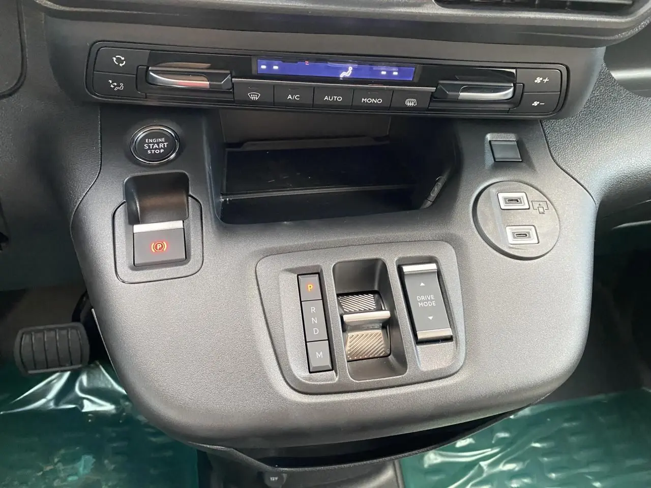 Vue rapprochée de la console centrale noire du Peugeot Partner Fourgon 2025 avec commandes de boîte et climatisation.