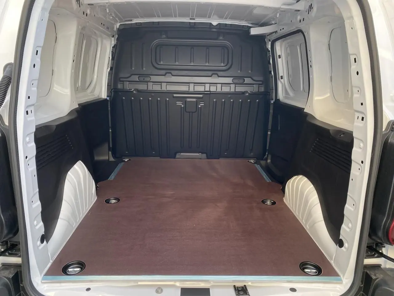 Vue intérieure arrière du Peugeot Partner Fourgon blanc, montrant la zone de chargement avec plancher en bois et anneaux d’arrimage.