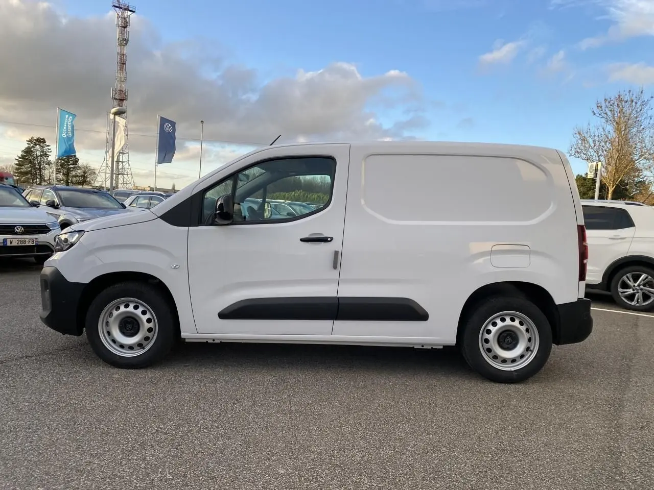 Vue latérale droite d’un Peugeot Partner Fourgon blanc avec porte coulissante et jantes tôles grises.