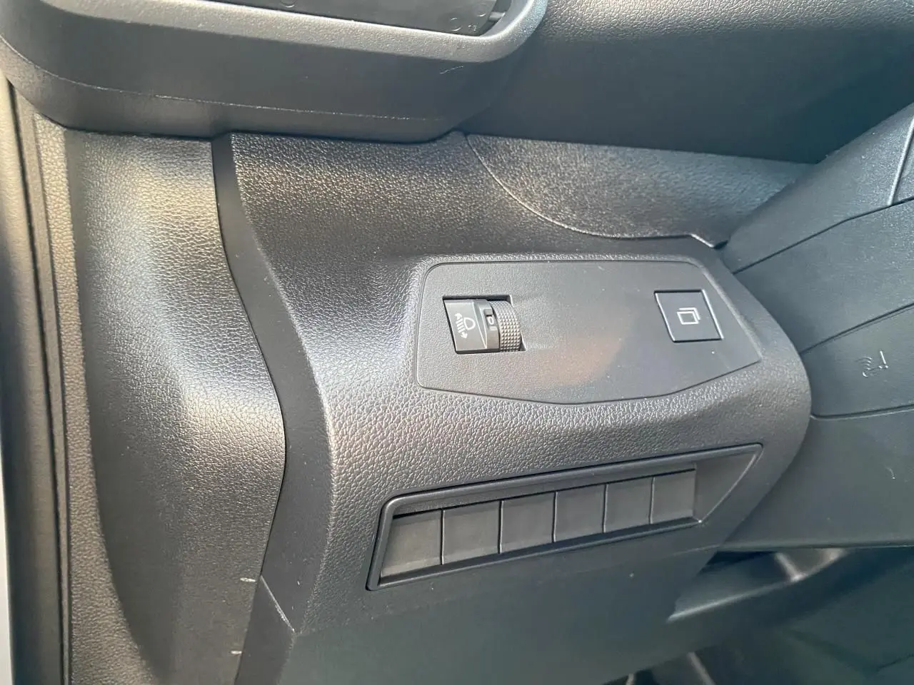 Détail du tableau de bord côté gauche du Peugeot Partner Fourgon blanc, avec commandes d'éclairage et boutons.