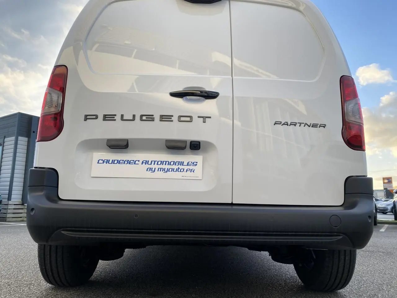 Vue arrière du Peugeot Partner Fourgon blanc, mettant en valeur les portes battantes et le pare-chocs noir.
