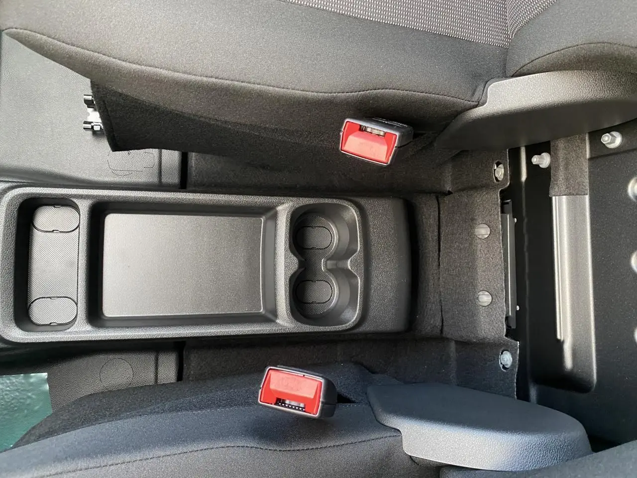 Vue plongeante sur la console centrale noire avec porte-gobelets et ceintures rouges du Peugeot Partner Fourgon blanc.