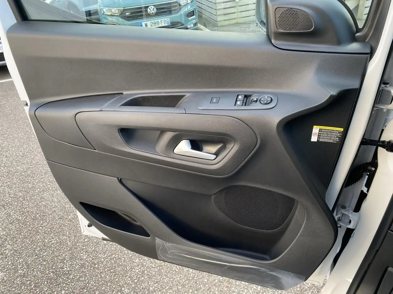 Vue rapprochée de la porte avant droite blanche du Peugeot Partner Fourgon avec commandes électriques et haut-parleur intégré.