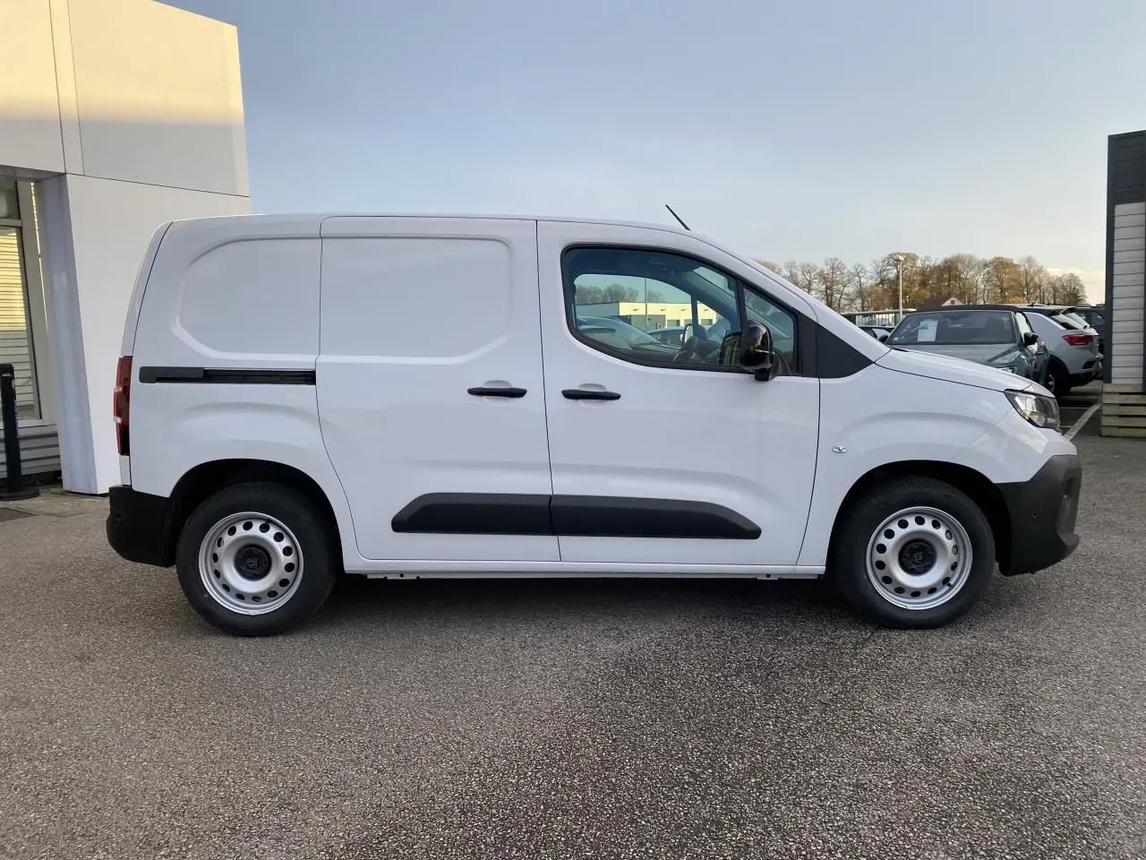 Vue de profil côté gauche d'un Peugeot Partner Fourgon blanc avec portes latérales et jantes tôles grises.