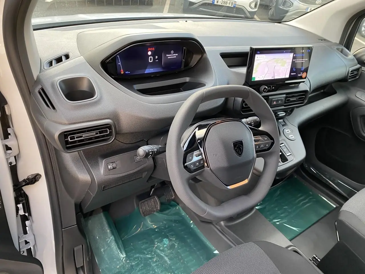 Vue intérieure côté conducteur du Peugeot Partner Fourgon blanc 2025, avec tableau de bord numérique et écran tactile central.