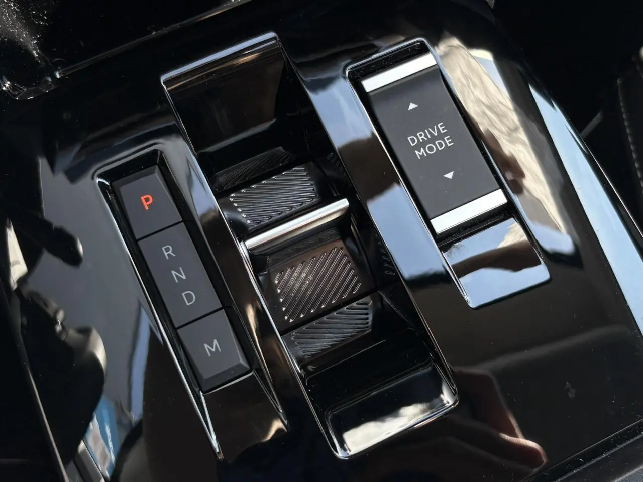 Vue rapprochée de la console centrale noire brillante avec commandes de boîte auto et sélection Drive Mode d'une Citroën C4 Hybrid 2025.