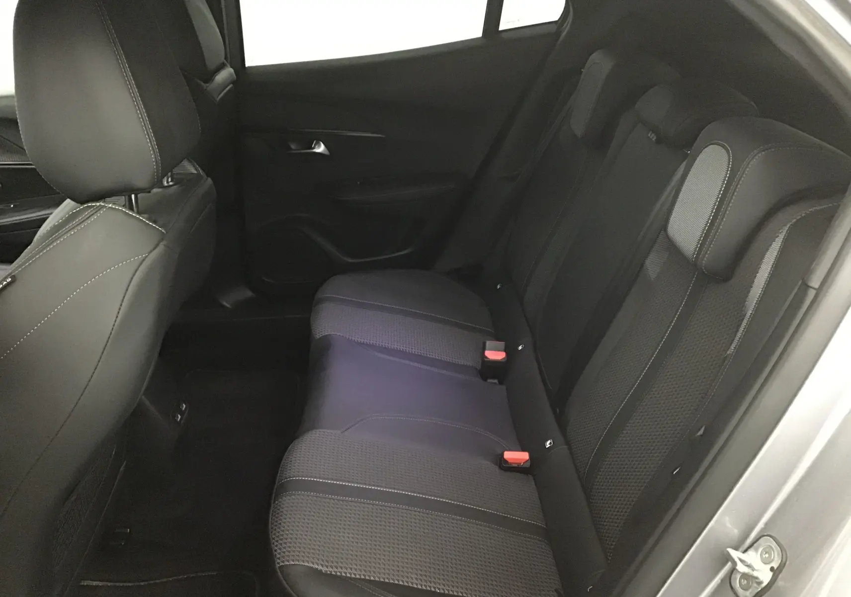 Vue côté droit de la banquette arrière en tissu noir du Peugeot 2008 électrique gris Artense, avec appuie-têtes et ceintures visibles.