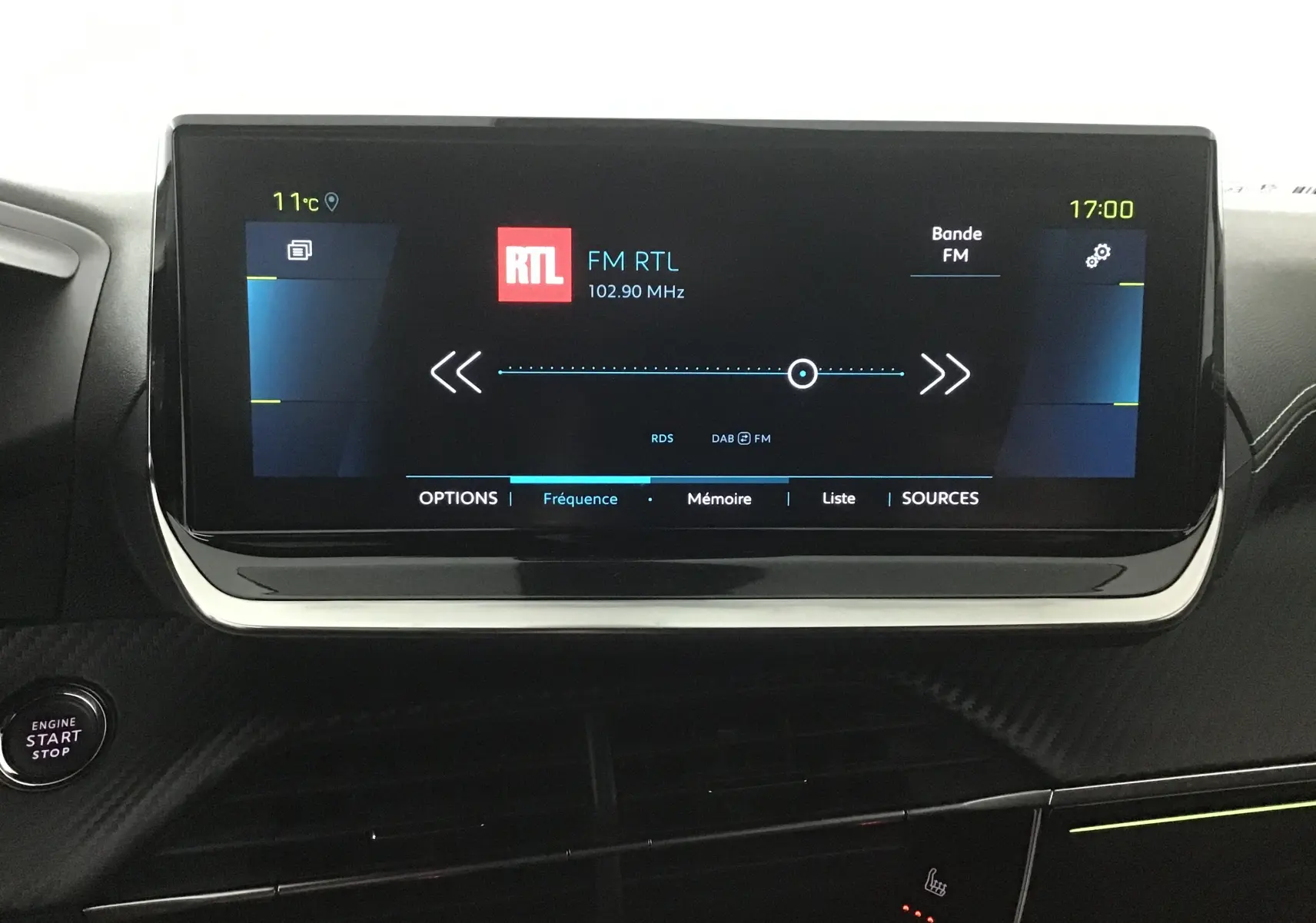 Écran tactile central du tableau de bord du Peugeot 2008 électrique gris, affichant la radio FM RTL à 17h00.