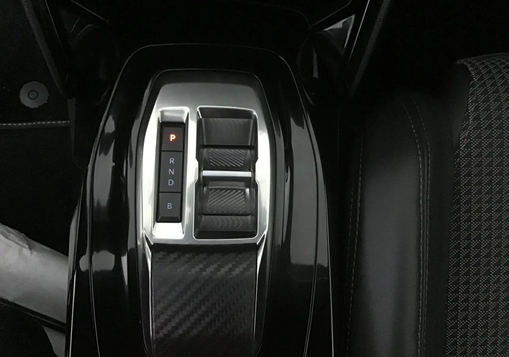 Gros plan sur la console centrale noire brillante avec sélecteur de boîte automatique du Peugeot 2008 électrique 2022.